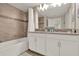 Well-lit bathroom with a double sink vanity, bathtub, and tiled walls at 4981 Windermere Ave, Kissimmee, FL 34746