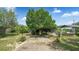 Spacious backyard featuring a large tree, small palm trees, and a screened in porch with furniture at 505 Oak Dr, Tavares, FL 32778
