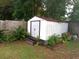 White storage shed provides ample outdoor storage with surrounding landscaping and a wooden fence at 505 Oak Dr, Tavares, FL 32778
