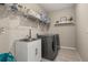 Functional laundry room with modern washer/dryer, sink, and shelving for storage at 5133 Citrus Leaf Blvd, Winter Garden, FL 34787