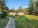 Lush backyard features a beautiful green lawn, mature trees, and a well-manicured landscape that provides shade at 600 Lake Butler Ave, Osteen, FL 32764