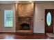Living room featuring a striking brick fireplace and hardwood flooring, lit by a window at 600 Lake Butler Ave, Osteen, FL 32764
