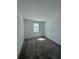 Bright bedroom with neutral walls, plush gray carpet, and natural light from the window at 7717 Stone Creek Trl, Kissimmee, FL 34747