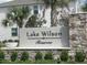 Landscaped entrance sign for Lake Wilson Reserve, accented by palm trees at 7717 Stone Creek Trl, Kissimmee, FL 34747