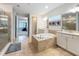 Bathroom with large tub, separate shower, and dual vanities with marble countertops at 9071 Woodland Forest Rd, Orlando, FL 32836