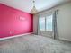 Bright bedroom with a pink accent wall, plush carpet and a decorative chandelier at 9071 Woodland Forest Rd, Orlando, FL 32836