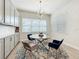Dining area features modern chandelier, a round glass table, and gray and blue upholstered chairs at 9071 Woodland Forest Rd, Orlando, FL 32836
