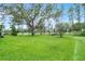 View of the expansive backyard featuring lush green grass and mature trees, creating a serene outdoor space at 909 Troon Cir, Davenport, FL 33897