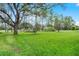 Lush green backyard features mature trees and manicured lawn, providing a peaceful and private outdoor retreat at 909 Troon Cir, Davenport, FL 33897