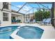 Hot tub with waterfall feature inside a screened-in lanai, offers the ultimate backyard relaxation spot at 909 Troon Cir, Davenport, FL 33897