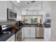 Modern kitchen with stainless appliances, white cabinets, and view to living and dining spaces at 909 Troon Cir, Davenport, FL 33897