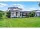 The backyard showcases a screened pool area with comfortable seating, surrounded by tropical plants and well-maintained lawn at 909 Troon Cir, Davenport, FL 33897