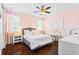 Charming pink bedroom with hardwood floors, decorative flower wall hangings, and natural light at 10067 Mere Pkwy, Orlando, FL 32832