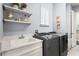 Well-organized laundry room with modern washer and dryer, sink, and shelving for storage at 10067 Mere Pkwy, Orlando, FL 32832