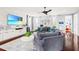 Open living room with large sectional sofa, modern ceiling fan, and built-in shelving with beach scene on TV at 10067 Mere Pkwy, Orlando, FL 32832