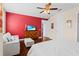 Stylish main bedroom with red accent wall, hardwood floors, white furniture, and modern ceiling fan at 10067 Mere Pkwy, Orlando, FL 32832