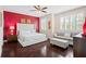 Bright bedroom with hardwood floors, red accent wall, white furniture set, and natural light from plantation shutters at 10067 Mere Pkwy, Orlando, FL 32832