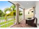 Covered patio featuring brick flooring, a white railing, and a lovely palm tree view at 10067 Mere Pkwy, Orlando, FL 32832