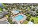 Aerial view of a community pool with an abundance of lounge chairs, palm trees, and bright orange umbrellas at 10067 Mere Pkwy, Orlando, FL 32832