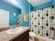 Bathroom with blue walls, granite countertop and a colorful shower curtain at 12606 Old Plantation Ln, Orlando, FL 32824