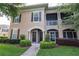 Two-story condo with a beige stucco exterior, brown shutters, manicured landscaping, and covered porches at 14205 Falls Church Dr # 2012, Orlando, FL 32837
