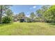 View of home's back exterior with screened-in patio and expansive yard, ideal for outdoor activities at 1431 Jack Calhoun Dr, Kissimmee, FL 34741
