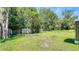 Spacious, grassy backyard surrounded by trees and a wooden fence, offering a private outdoor space at 1431 Jack Calhoun Dr, Kissimmee, FL 34741