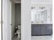 Bathroom with a gray vanity, dual sinks, a large mirror, and a glass enclosed shower, along with natural light from a window at 1513 Resolute St, Celebration, FL 34747