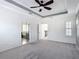 Spacious main bedroom with tray ceilings, neutral walls, ceiling fan, plush carpeting and access to the ensuite bathroom at 1513 Resolute St, Celebration, FL 34747