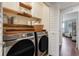 Convenient laundry room with modern washer and dryer, storage cabinets, and wooden shelving at 15540 Blackbead St, Winter Garden, FL 34787