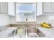 Close up of a kitchen sink with granite countertops and white cabinets at 1912 Maury Rd, St Cloud, FL 34771