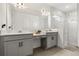Bathroom featuring dual sinks, white cabinets, a large mirror and marble shower at 19267 Allium Pl, Orlando, FL 32827