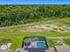 Aerial view of a home with a screened in pool, tiki bar, and wooded backyard at 209 Willow Bend Dr, Davenport, FL 33897