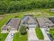 Aerial view of community homes with solar panels, a pool, and green space surrounded by a beautiful wooded landscape at 209 Willow Bend Dr, Davenport, FL 33897
