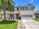Charming two-story home with well-maintained landscaping, a palm tree, a covered porch and a two car garage at 209 Willow Bend Dr, Davenport, FL 33897