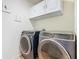 This well-lit laundry room includes front-loading washer and dryer with white cabinetry and ample space at 209 Willow Bend Dr, Davenport, FL 33897