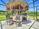 The outdoor kitchen features a stainless steel grill, bar seating, and a beautiful thatched roof for shade at 209 Willow Bend Dr, Davenport, FL 33897