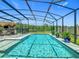 Enclosed pool area with large pool, heated spa, outdoor kitchen, and tropical plants ensures year-round enjoyment at 209 Willow Bend Dr, Davenport, FL 33897