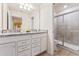Bright bathroom featuring a double sink vanity with granite countertops and a tiled shower with glass doors at 2161 Lelani Cir, Davenport, FL 33897