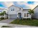 Charming two-story home with a manicured lawn, a paved driveway, and decorative palm trees at 2161 Lelani Cir, Davenport, FL 33897
