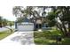 Blue single-story home with attached garage, mature trees, and a well-maintained front yard with green grass at 238 Sunridge Woods Blvd, Davenport, FL 33837