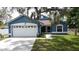 Charming blue single-story home featuring a two-car garage, well-manicured lawn, and a inviting entryway at 238 Sunridge Woods Blvd, Davenport, FL 33837