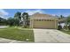 Inviting single-story home with a two-car garage, lush lawn, and mature palm trees at 2401 Cedarfield Ln, Kissimmee, FL 34744