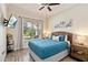 Cozy bedroom featuring a ceiling fan, plush blue bedding, wood-look flooring, and ample natural light from the window at 2736 Southland St, St Cloud, FL 34772