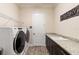 Spacious laundry room featuring modern washer and dryer set, granite countertops, storage cabinets, and a sink at 2736 Southland St, St Cloud, FL 34772