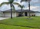 Beautiful single-story home with lush green lawn and mature palm trees at 306 Clermont Dr, Kissimmee, FL 34759