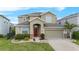 Charming two-story home featuring a two-car garage, red door, and well-maintained landscaping at 3853 Cortland Dr, Davenport, FL 33837