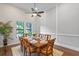 Bright dining room with a wood table set for eight, modern ceiling fan, and large windows to a well-kept yard at 4224 Clarice Estates Dr, Windermere, FL 34786