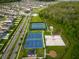 High angle view of community sports courts including tennis, basketball, and volleyball near homes and trees at 4338 Finch Ln, Kissimmee, FL 34746
