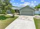 View of the front of the single-story home with a concrete driveway, lush grass and mature trees at 4607 Pine Lake Dr, St Cloud, FL 34769